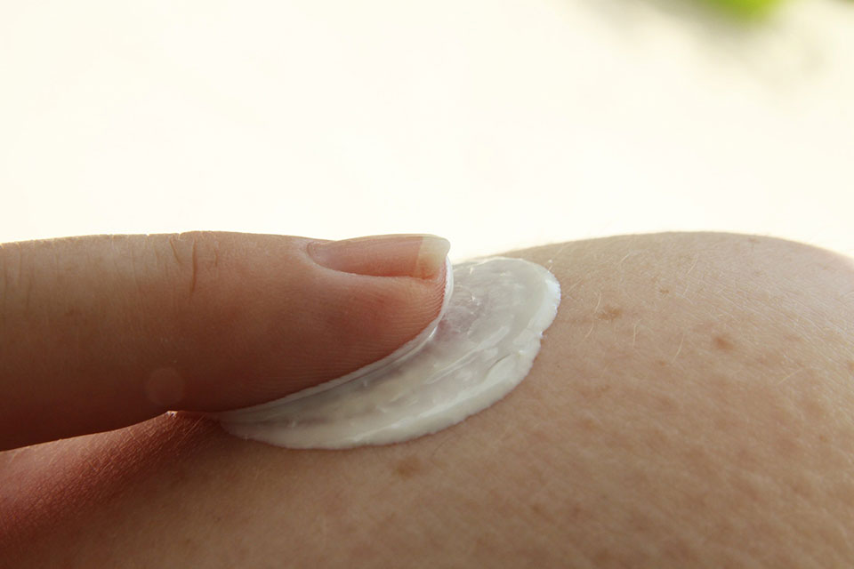 Finger rubbing sunscreen into skin.