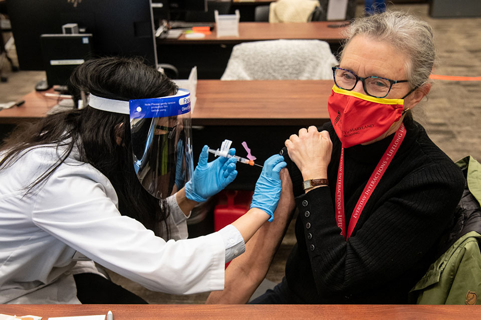 Fourth-year student pharmacist Amy Chen administers the Moderna COVID-19 vaccine to Jane M. Kirschling, PhD, RN, FAAN, dean of the School of Nursing.