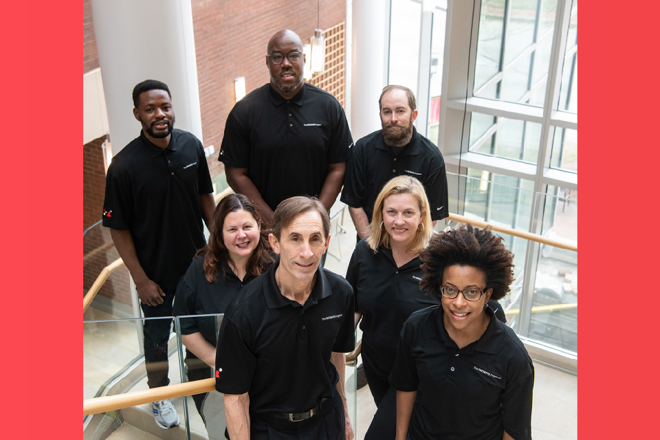 A group of people in black polo shirts stand on a staircase.