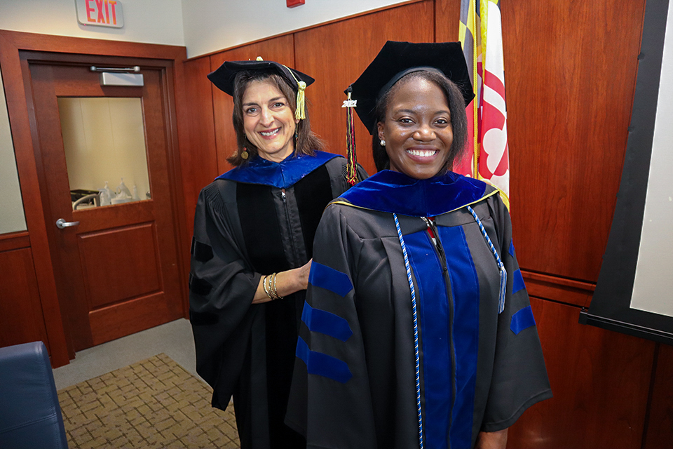 A PhD student is hooded by Dr. Susan dosReis.