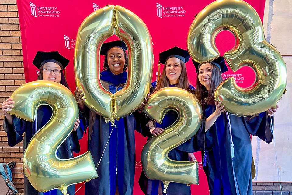 Doctoral students holding balloons that say 2023.